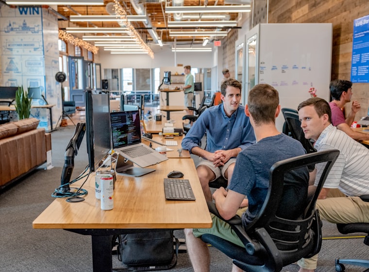 Three people working together at a shared desk.